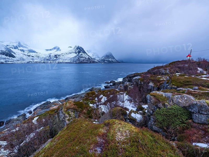 Small lighthouse at the end of Husøy island with a view across the fjord to the sea, Senja island, Troms, Norway