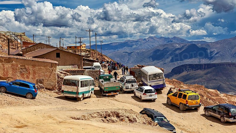 Series of vehicles on a winding road in a mountainous region under a blue sky, The silver mines of Potosi on Cerro Rico in Bolivia