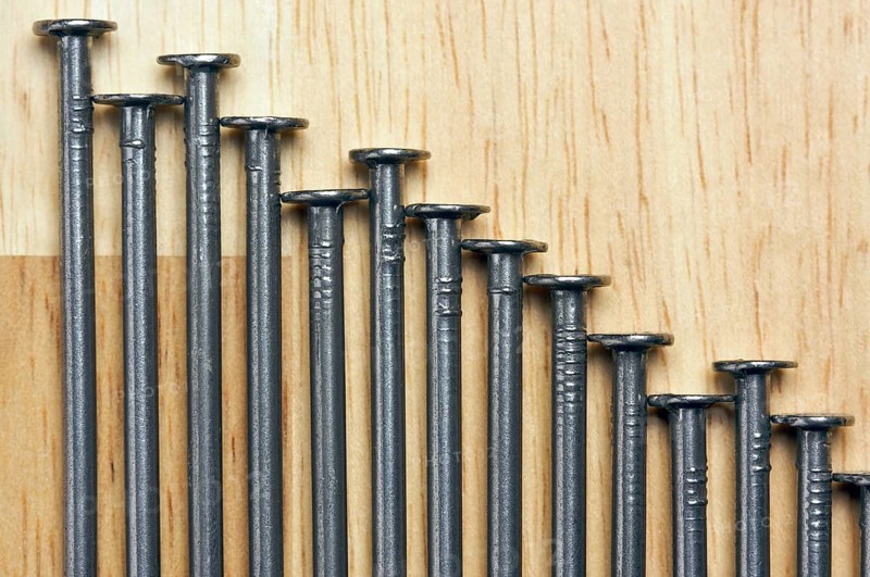 Declining Graph of Nails on a Wood Background