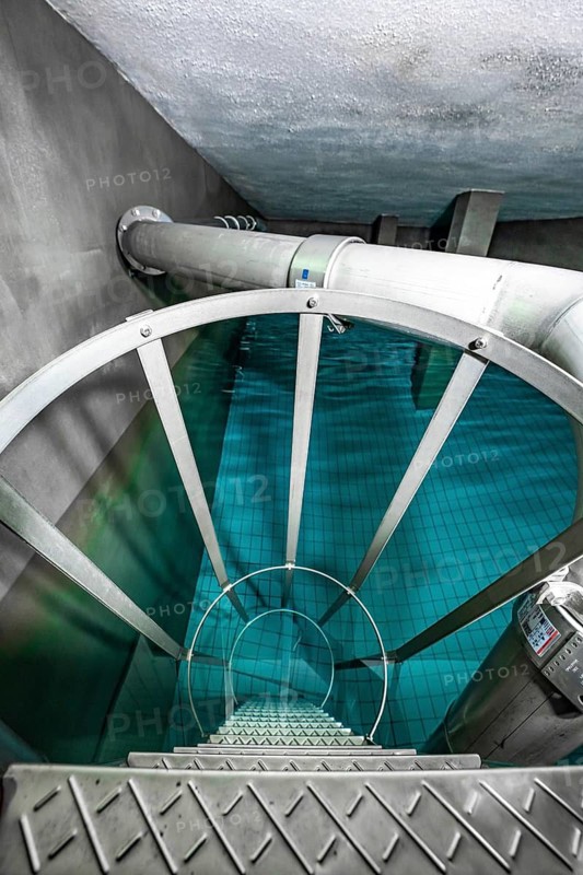 Metallic spiral staircase leads to an underground water basin with bluish water, ENCW Netze Calw waterworks, Calw, Black Forest, Germany