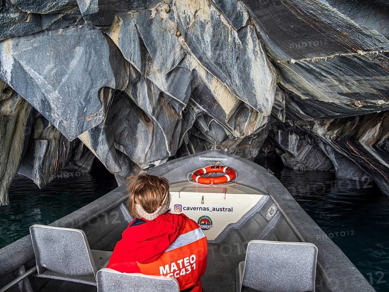 Woman sitting at the front of a tour boat, excursion boat inside the marble caves, Puerto Sanchez, lake Lago General Carrera, Chile