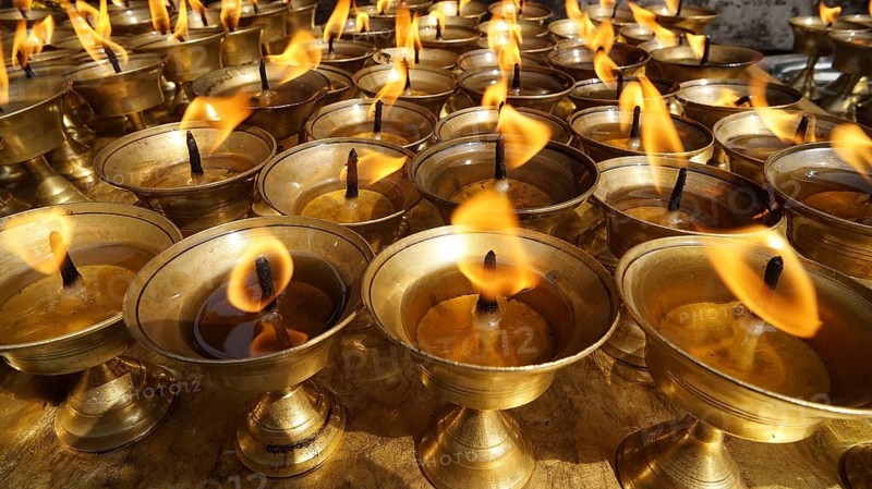 An arrangement of oil lamps with burning flames creates a meditative mood, Bodnath, Kathmandu, Nepal