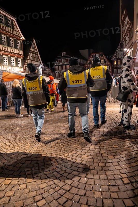 Group of people in yellow waistcoats at night in front of half-timbered houses on cobblestones, carnival, Calw, Black Forest, district of Calw, Germany