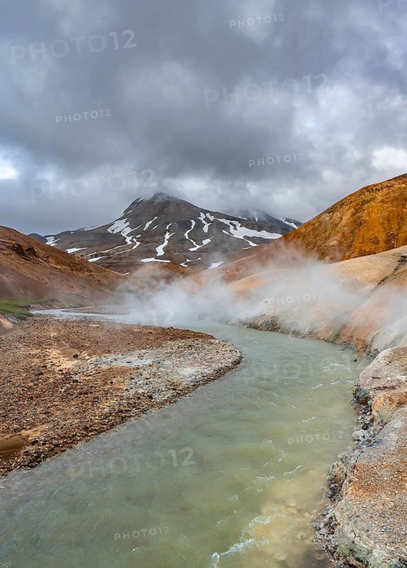Steaming stream between colourful rhyolite mountains with snowfields, Hveradalir geothermal area, Kerlingarfjöll, Icelandic highlands, Iceland