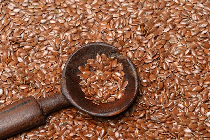 Linseed with wooden spoon, seeds of the common flax (Linum usitatissimum)