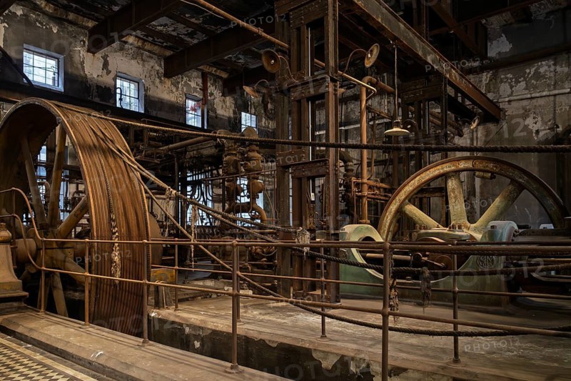 Historic steam engine with large flywheels and rope drive in abandoned meat factory, rusty machine shop with peeling plaster, Frigorífico Anglo, Fray Bentos, Río Negro Department, Uruguay