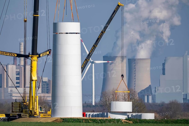 Construction site of the new Bedburg 3 wind farm, on recultivated open-cast mining site, 9 wind power plants with an output of 60 megawatts are newly built, installation of the wind turbine tower, in the background the Neurath lignite power plant, operated by RWE and the city of Bedburg, North Rhine-Westphalia, Germany