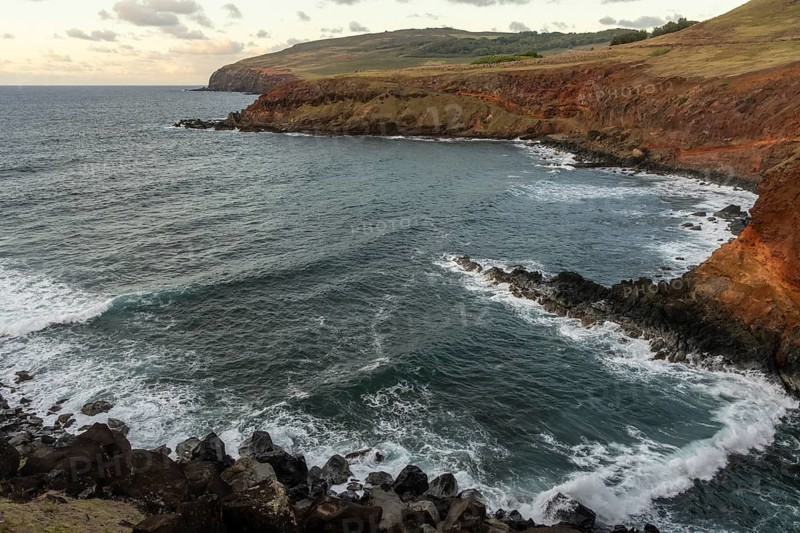 Rocky cliffs with lava rock and surf, reddish volcanic rocks in the evening light, north-east coast, Easter Island (Rapa Nui), Chile