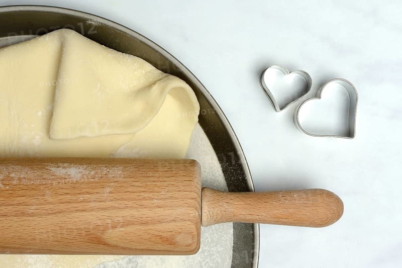 Rolled dough on cake tray with dough rollers and cookie cutters