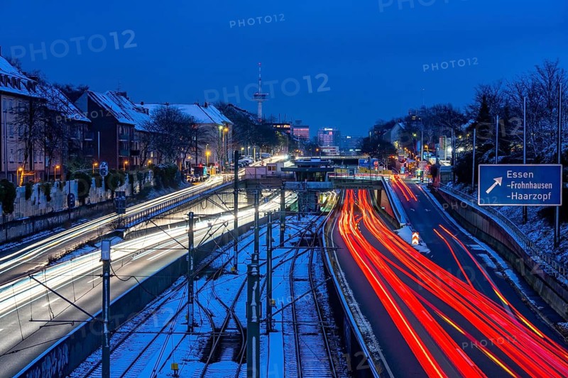 Autobahn A40, Ruhrschnellweg, near Essen at the Frohnhausen junction, evening traffic in winter, residential buildings directly on the 4-lane motorway, North Rhine-Westphalia, Germany