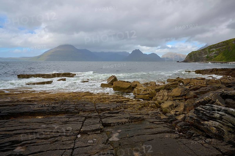 Rocky coastline with waves and views of distant mountains and cloudy sky, Elgol Beach, Elgol, Isle of Skye, Scotland, United Kingdom, United Kingdom