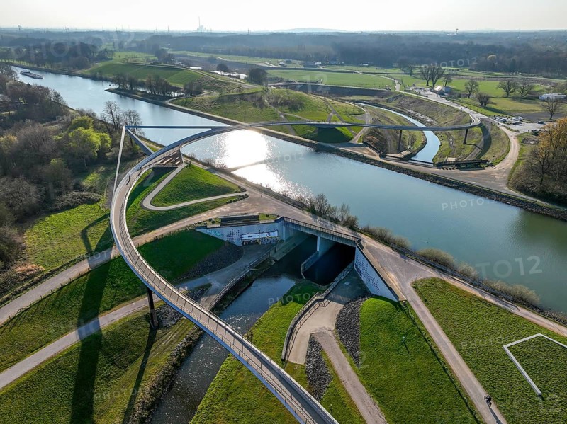 Castrop-Rauxel, North Rhine-Westphalia, Ruhr region, Germany - Sprung bridge over the Emscher, a footbridge and cycle path across the Emscher and the Rhine-Herne Canal. EMSCHERLAND adventure park, new nature and water adventure park on the restored Emscher, at the Emscher water cross with the Rhine-Herne Canal on the city limits of Recklinghausen and Castrop-Rauxel. Flood protection through area expansion. The ecological focus at the confluence of the Suderwicher Bach and Emscher rivers will also be a future garden of the IGA 2027 International Garden Exhibition. Before the restoration, the river system of the Emscher was an open, aboveground waste water channel, mixed water channel with surface water and waste water