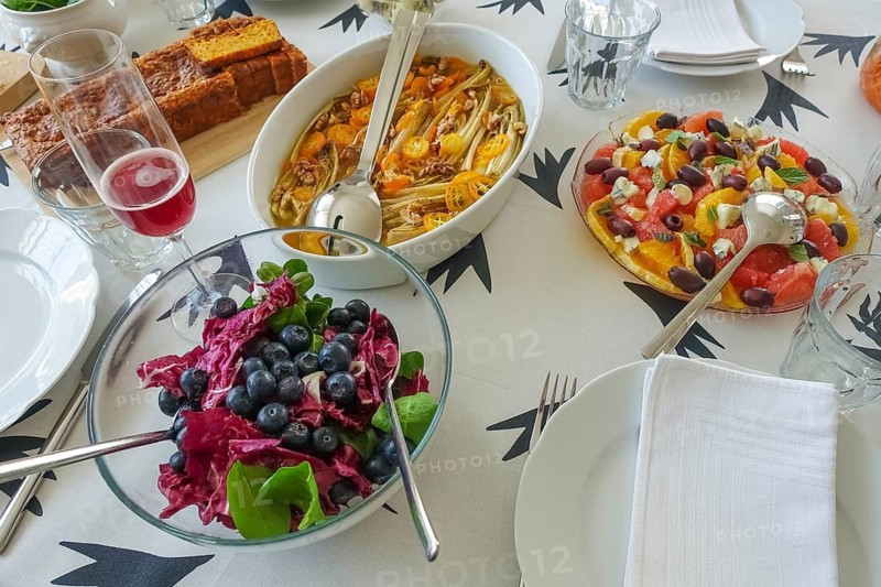 Vegetarian cuisine, salad with blueberries, radicchio (Cichorium intybus var. foliosum), chicory at the back, salad, winter vegetables, kumquats (Fortunella), dwarf oranges, sliced citrus fruit, salad servers, bowl, starter on the right, citrus fruit, orange slices, grapefruit, black olives, Roquefort, blue cheese, sheep's cheese, herbs, mint, carrot bread on the left, table setting, plate, cutlery, arranged, healthy, food photography, studio, Germany