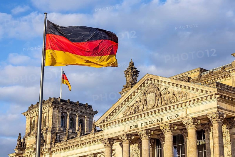 Reichstag building Berlin with German flags. Exterior view with dark clouds. Berlin, Germany
