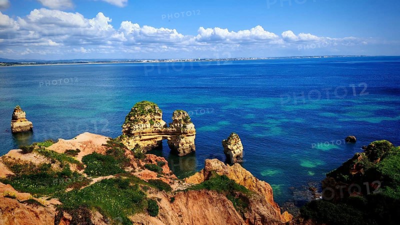 Wide views of and rock formations and rock arches in the azure blue sea, Praia do Camilo, Lagos, Algarve, Portugal
