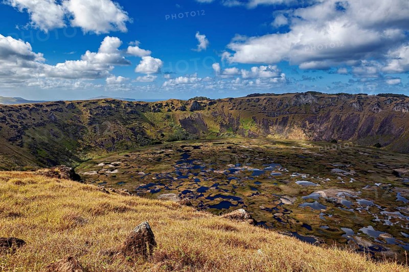 Far-reaching views of the crater and its surroundings under a blue, cloudy sky, Ranu Kau volcano on Easter Island in the Pacific Ocean