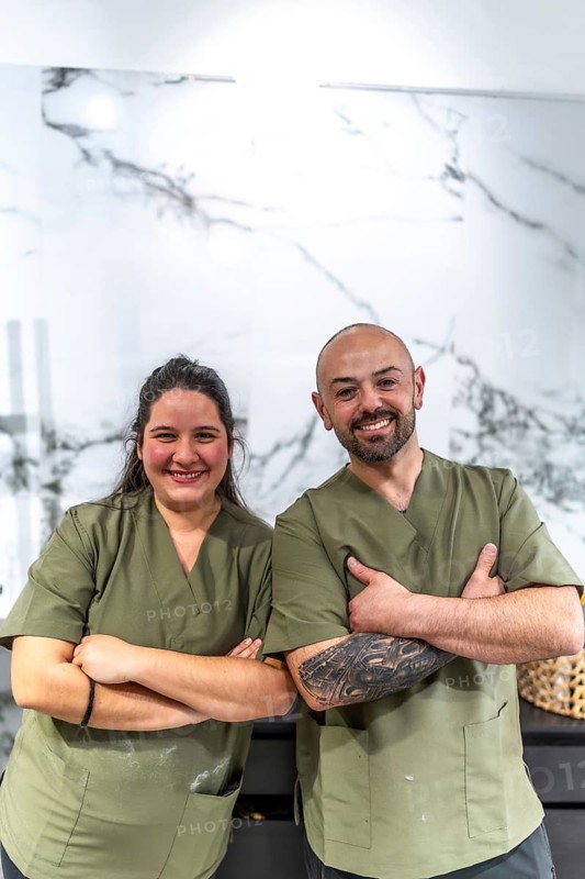 Two diverse healthcare workers standing confidently with crossed arms, wearing green medical scrubs and looking at the camera, symbolizing professionalism, teamwork, and reliable healthcare services