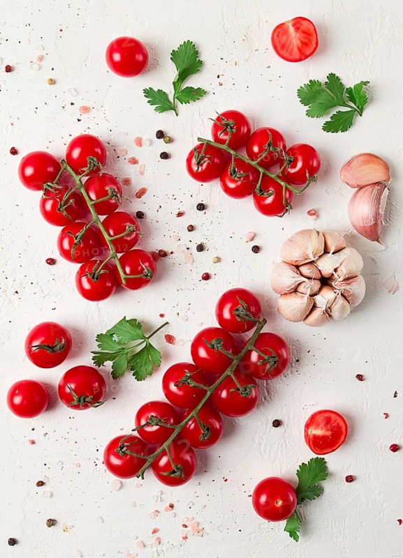Branch with mini cherry tomatoes, with spices and herbs, garlic, food background, top view, on a white background