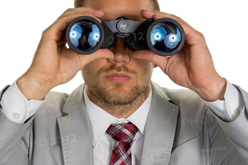 A manager (young entrepreneur) with binoculars looking for orders or jobs, studio shot