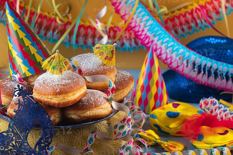 A plate of donuts surrounded by colorful party hats, streamers and garlands, carnival