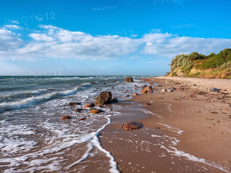 Unspoiled secluded stretch of coast with cliffs and boulders in the surf on the beach of the stormy Baltic Sea, foam crowns on the waves, near Rerik, Mecklenburg-Western Pomerania, Germany