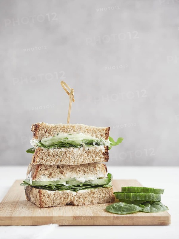 Cucumber and green spinach sandwich, cut in half and stacked, topped with a bamboo stick
