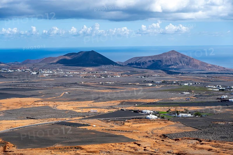 Dry volcanic landscape with houses and fields and volcanic craters, Lanzarote, Canary Islands, Spain