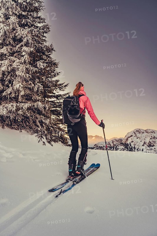A woman's ski tour at sunrise on the Tegelberg in the Allgäu in the Ammergebirge, Bavaria, Germany
