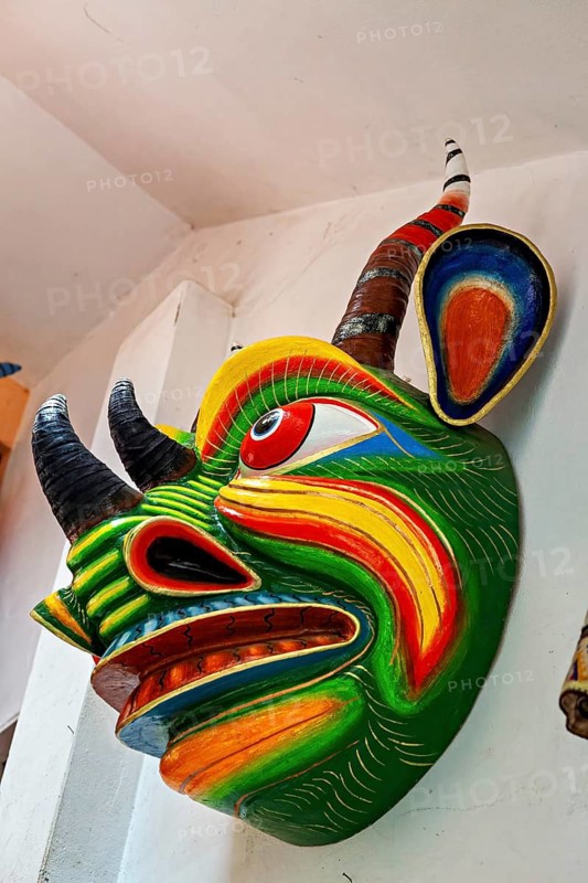 Side view of a colorful Tibetan demon mask with bright psychedelic colors on a wall corner, masks of mythical creatures in Ollantaytambo in the Andes of Peru
