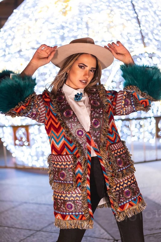 Christmas lights in the city, blonde model with a hat next to a giant illuminated ball in a fashionable pose, winter lifestyle