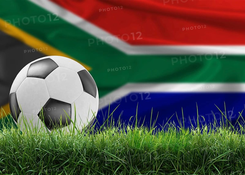 Soccer ball on pitch against South African flag in the background. Soccer ball on the grass with South Africa flag in the background