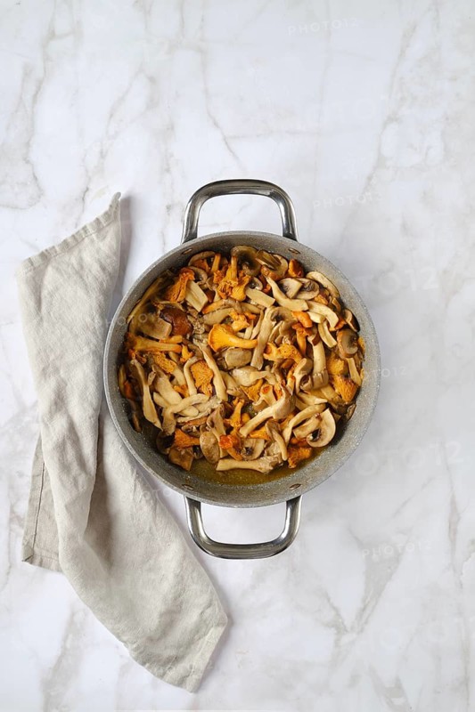 Overhead view of casserole with chopped champignon, chanterelles and oyster mushrooms