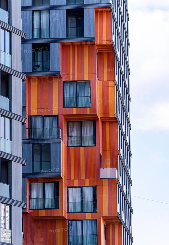 This image highlights modern architectural elements, featuring a mix of glass, concrete, and metal in a vibrant suburban building