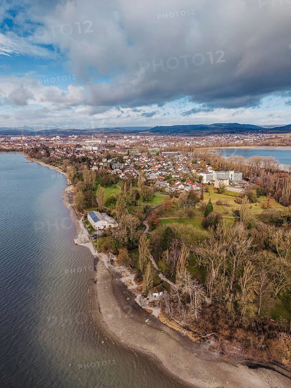 Aerial view of the Mettnau peninsula in western Lake Constance with winter vegetation with the Mettnaupark, Mettnaukur, behind it the town of Radolfzell, the Hegauberge Mountains on the horizon, Konstanz district, Baden-Württemberg, Germany