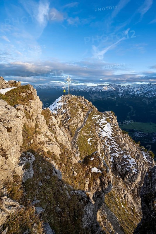 Mountaineer at the summit of the Kramerspitz with summit cross, at sunset, in autumn, Ammergau Alps, in autumn, Bavarian Alps, Bavaria, Germany