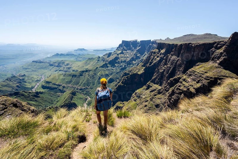 Young hiker looking at the impressive mountains and cliffs of the Drakensberg Mountains, hiking trail on the Sentinel Hiking Trail, Drakensberg, KwaZulu-Natal, South Africa