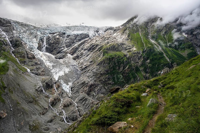 Hiking trail, cloudy mountain landscape with Grindelwald-Fiescherfirn glacier, Bernese Alps, Bernese Oberland, Switzerland