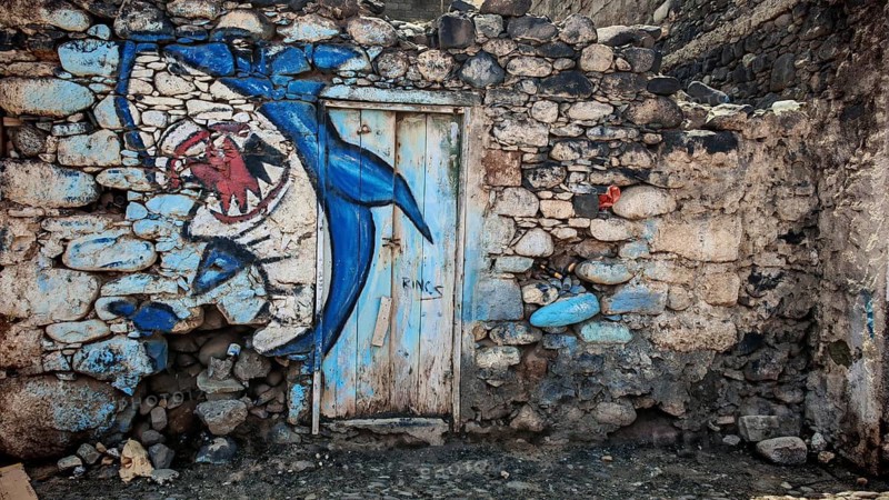 Blue shark wall mural, graffiti on dilapidated stone wall with door, Ribeira Grande, Santo Antao, Cabo Verde, Cape Verde