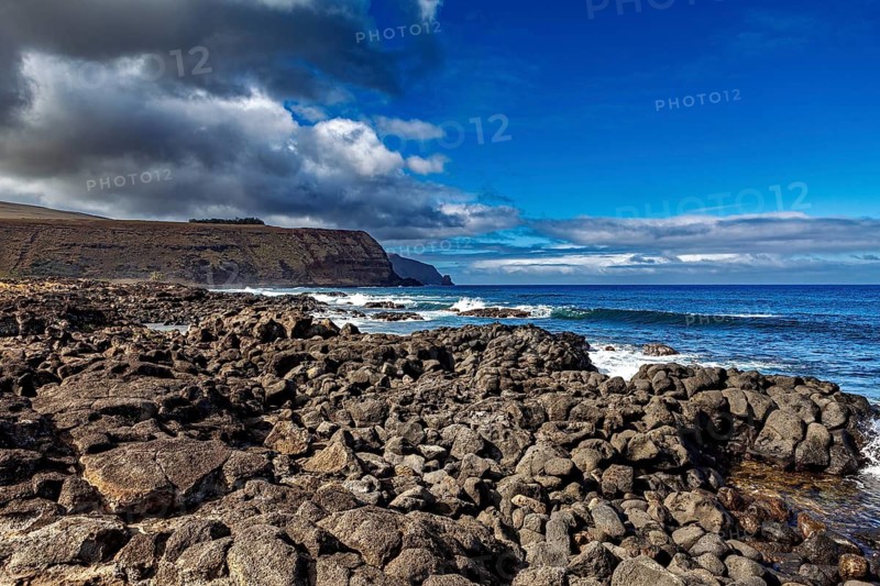 Rough rocky coast with dark clouds over a deep blue sea, the landscape of Easter Island in the Pacific Ocean