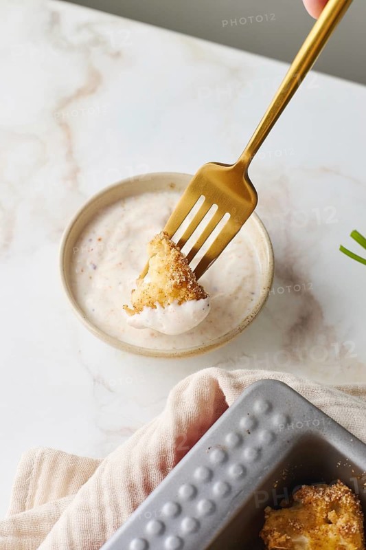 Top view of cropped unrecognizable person trying food with fork with delectable serving of baked cauliflower coated in breadcrumbs, dipped into a creamy cheese sauce