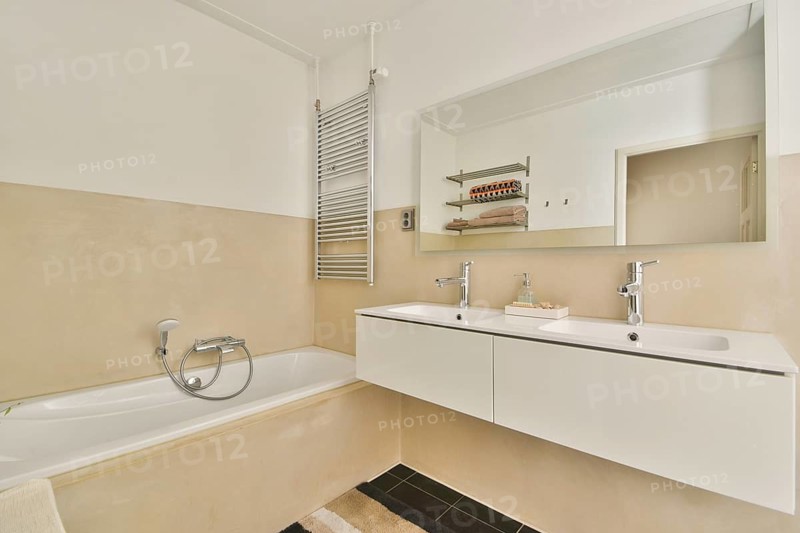A contemporary bathroom featuring a sleek double sink vanity, modern fixtures, and a spacious bathtub. Neutral tones and minimalist design create a calm, inviting atmosphere