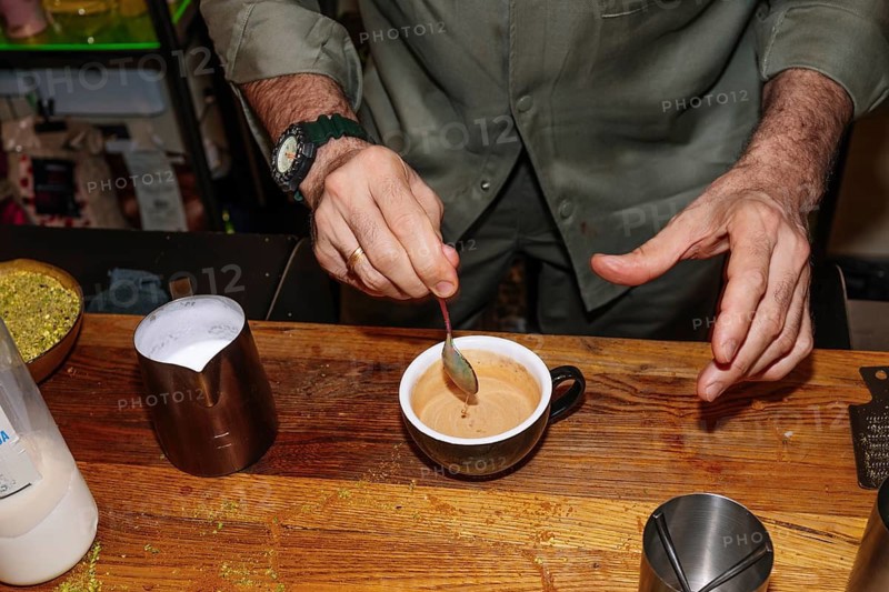 A barista skillfully stirs a freshly brewed specialty coffee in a cozy coffee shop setting. The scene captures the essence of artisanal coffee making with a focus on detail and quality