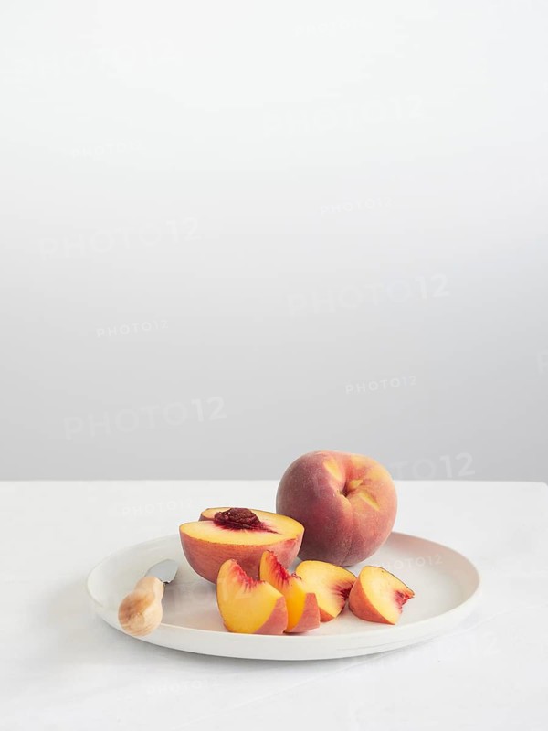 Ripe peaches cut into slices and halves on a plate on the table