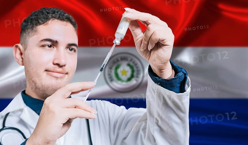 Doctor holding syringe on Paraguay flag background. Medical professional holding syringe with Paraguayan flag in the background