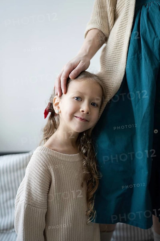 A young child leans against an adult, feeling comforted and loved The adult's hand gently rests on the child's head, symbolizing protection and affection