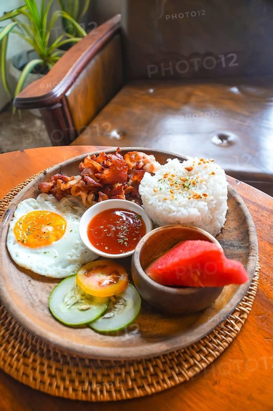 Enjoying a vibrant filipino breakfast in siargao island with crispy bacon, sunny side up eggs, heart shaped rice, fresh watermelon, and savory sauce