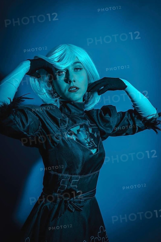Portrait of cosplay woman in black costume and a white wig in studio with blue led light
