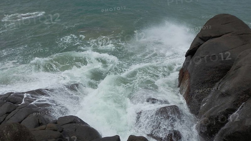 Strong waves break with spray over rocks on the coast, Sri Lanka