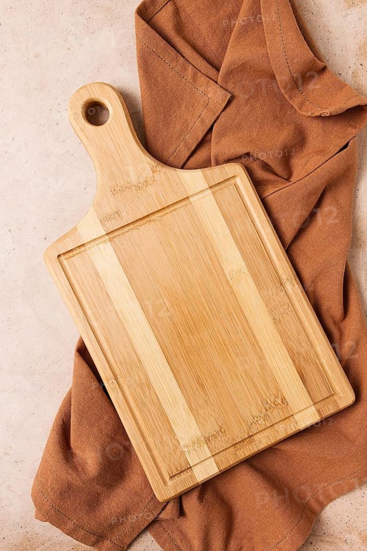 Cutting board, beige, unpainted, with a kitchen towel, on a beige background, top view