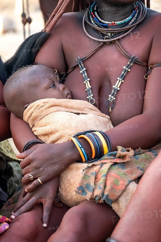 Himba woman holding a baby, traditional Himba village, Kaokoveld, Kunene, Namibia